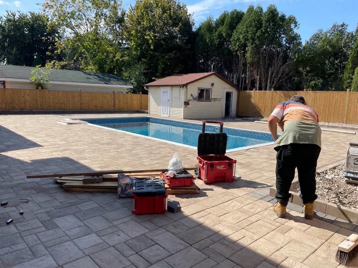 Interlock pavers being laid around an in-ground pool in Cornwall