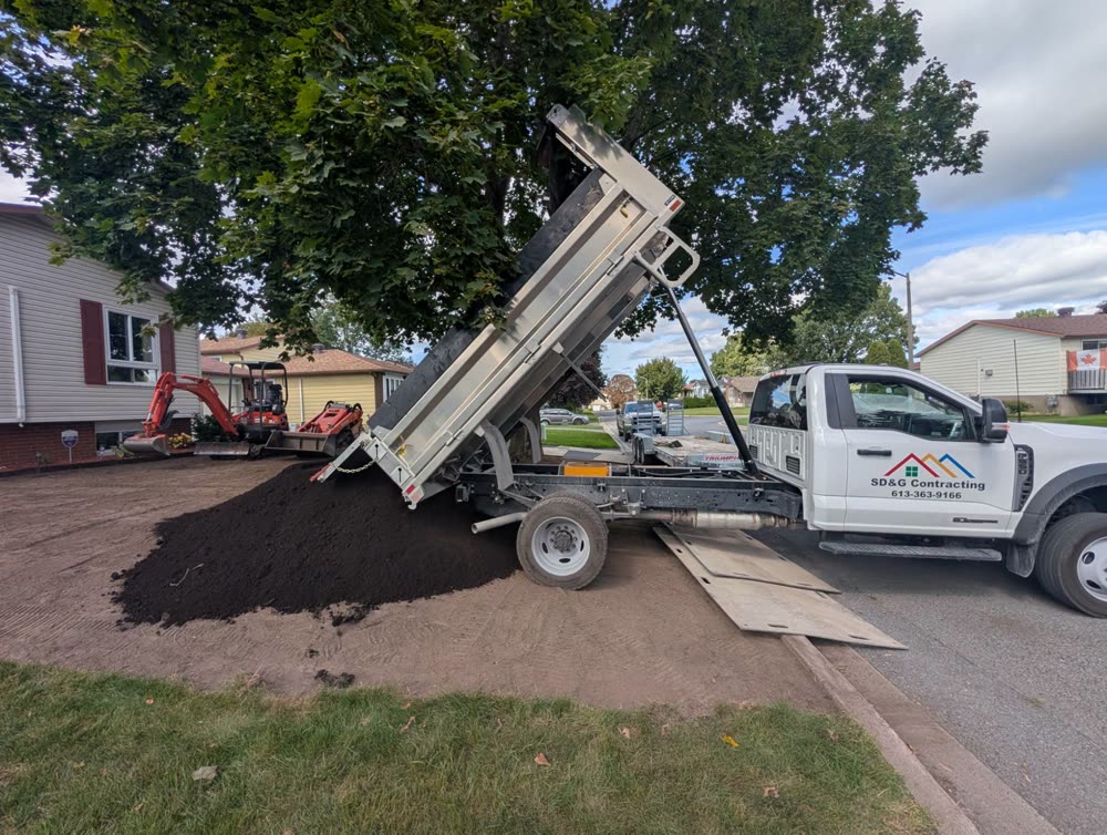 SD&G Contracting dump truck delivering screened topsoil onto a stripped front yard