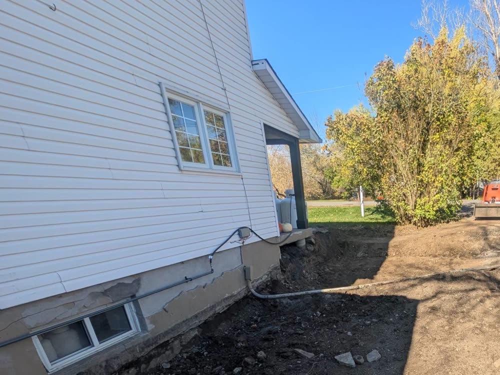 Excavated ground beside the house foundation, ready for a stone base