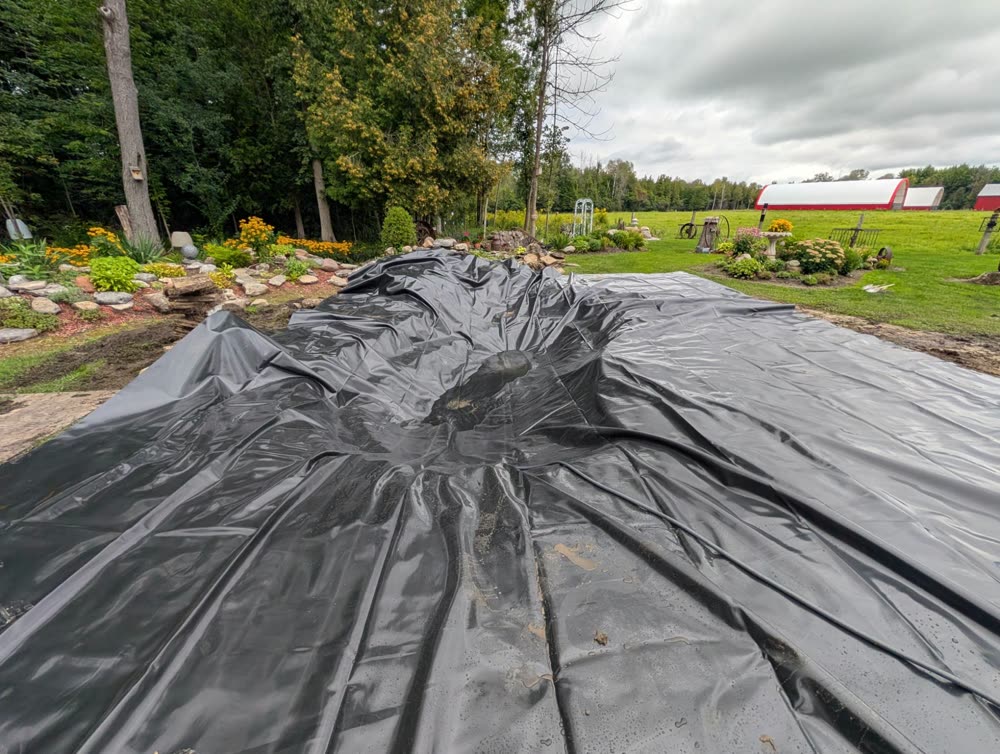 Black pond liner laid over the excavated pond