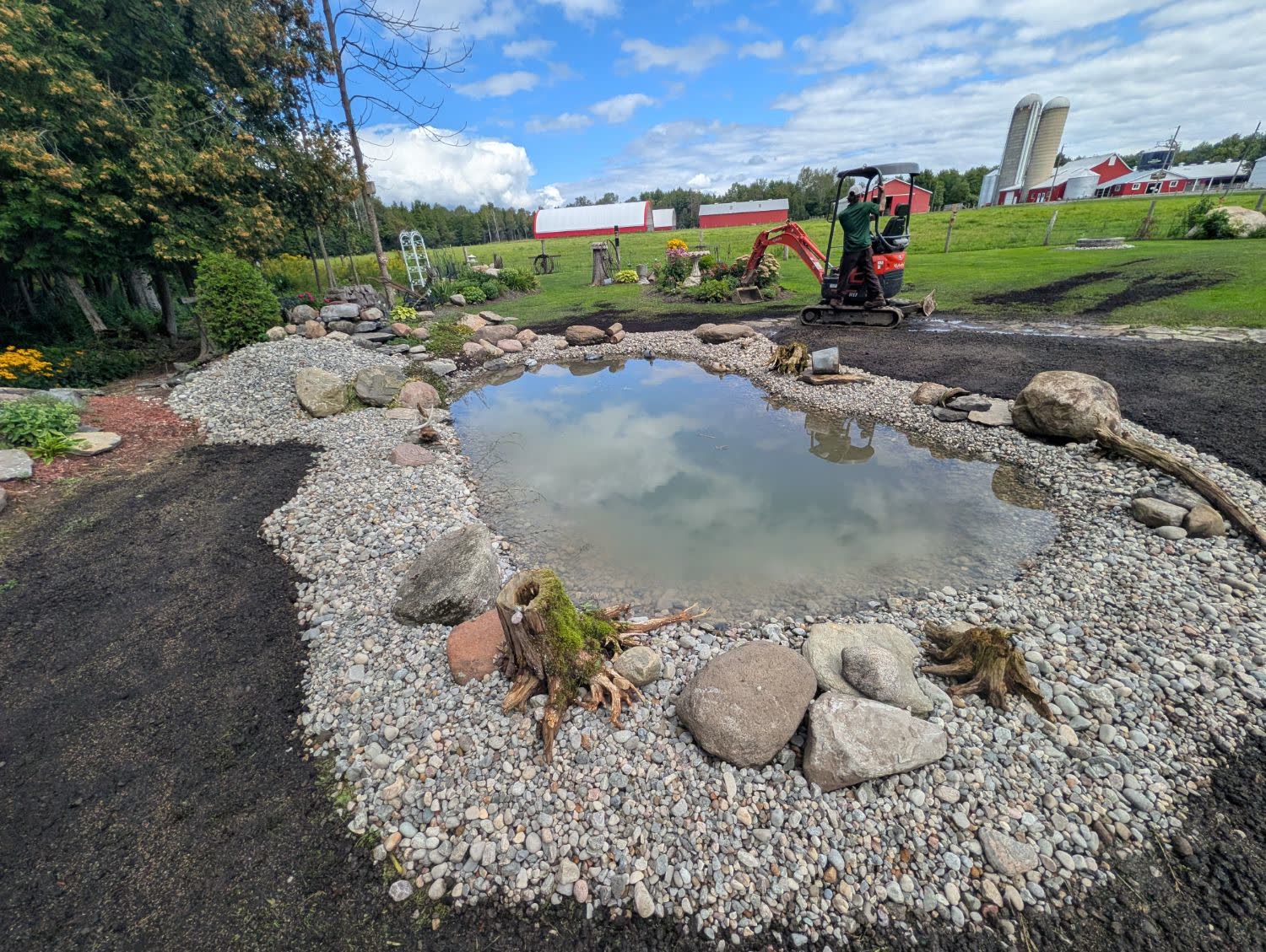 Finished backyard pond with river stone edging built by SD&G Contracting near Ingleside, Ontario