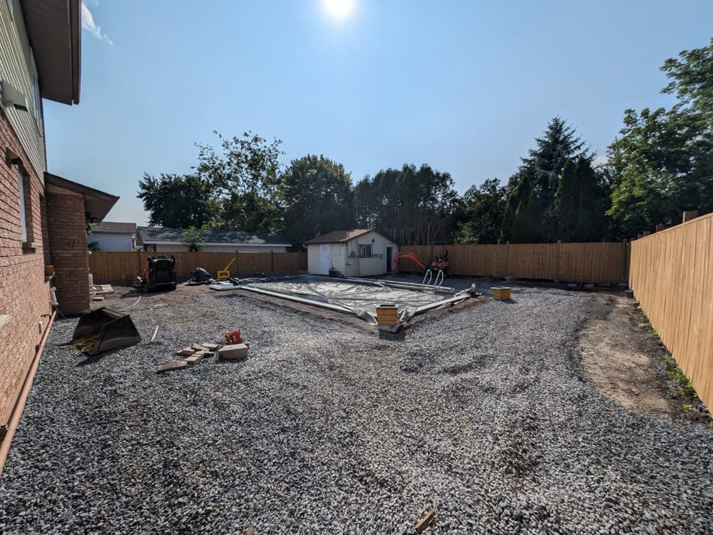 Compacted stone base spread across the yard around the pool