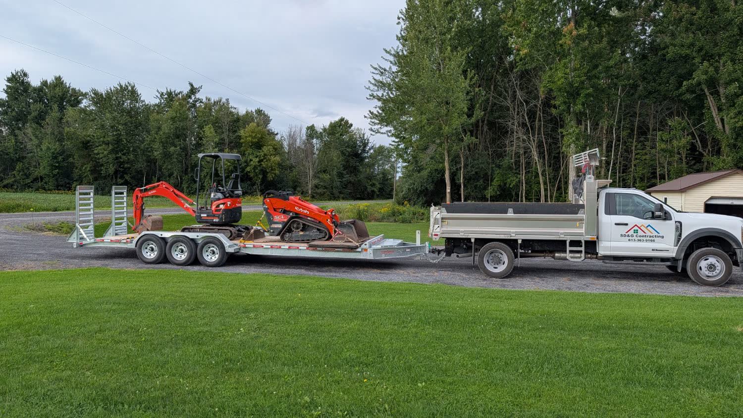 SD&G Contracting truck towing a trailer with a Kubota mini excavator and track loader in Cornwall, Ontario