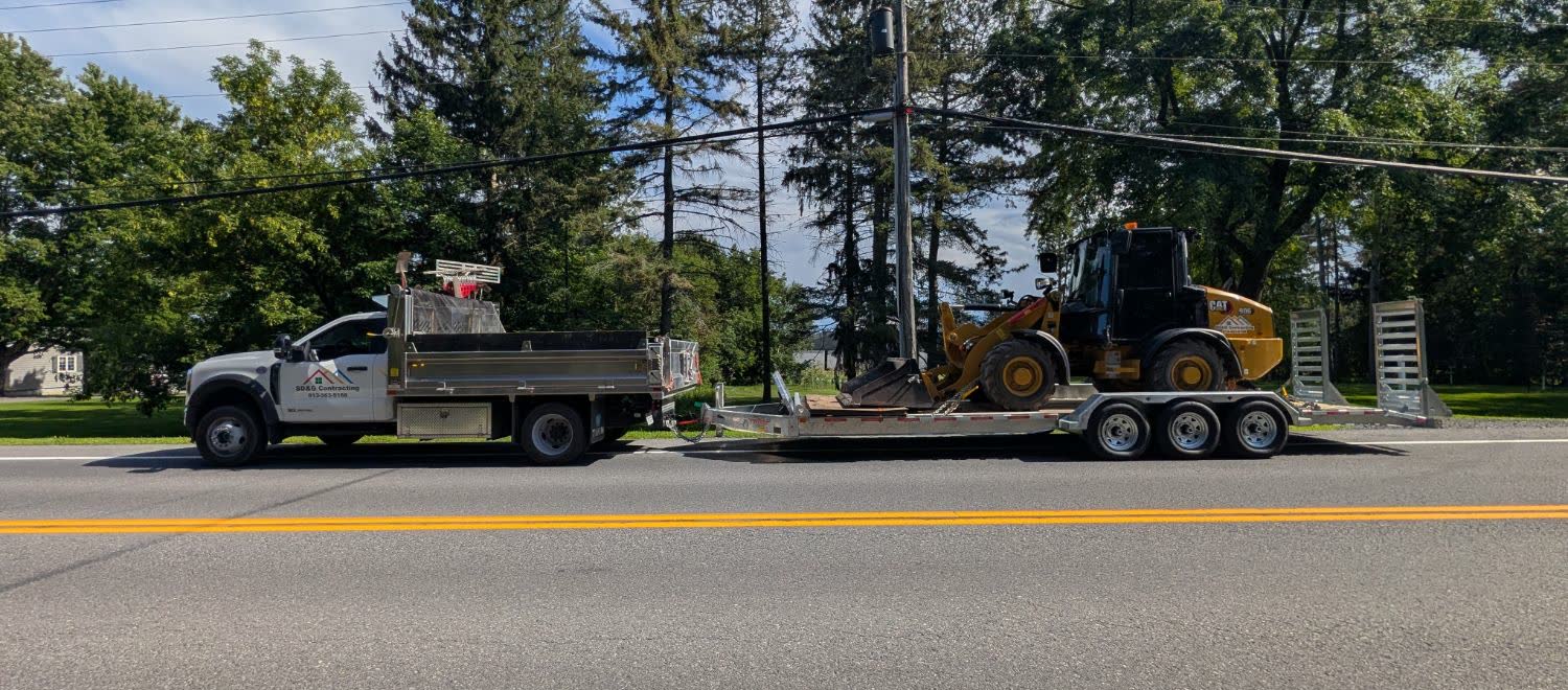 SD&G Contracting dump truck hauling a CAT wheel loader on a trailer in Cornwall, Ontario