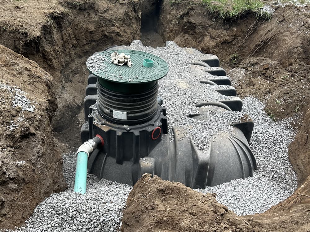 Underground water cistern bedded in clear stone during installation for an off-grid home